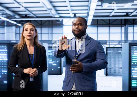 Teamworking engineers in server room using AR tech to implement and maintain security measures, protecting systems from unauthorized access. Data center colleagues using augmented reality Stock Photo