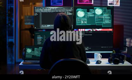Hacker arriving in hidden underground shelter with laptop, prepared to launch malware attack on websites. Scammer in apartment starting work on dangerous script that can breach security, camera A Stock Photo