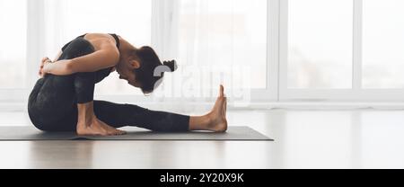 Young woman practicing yoga in a bright studio at morning Stock Photo