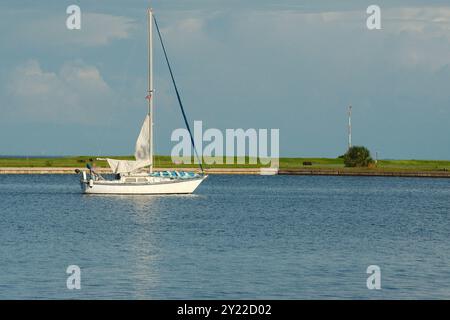 Demens Landing Park water towards jetty and Tampa Bay. In St. Petersburg, FL. Rocks in background small waves. White sailboats moves left to right. Stock Photo