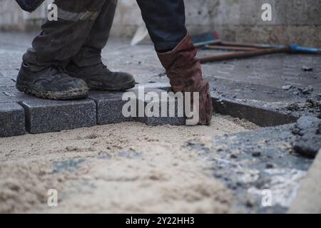 Laying Paving Stones on a Construction Site for a driveway or footpath requires skill and precision Stock Photo