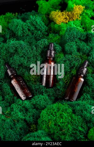 Brown glass dropper bottles arranged on green moss in a natural setting Stock Photo