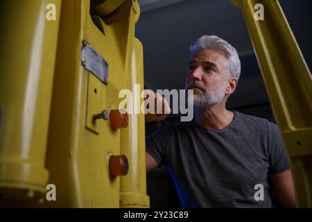 Engineer checking, servicing robotic arm. Concept of modern technology in industries, automated processes, robotics. Stock Photo