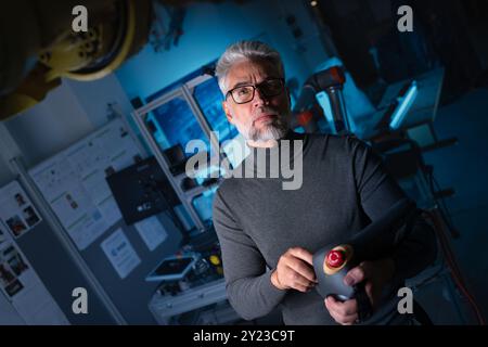 Automation engineer, technician holding remote controller of robotic arm. Concept of modern technology in industries, automated processes, robotics. Stock Photo