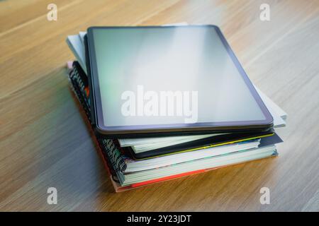 Books documents graphic tablet on top. Documents stack wooden table. Stock Photo