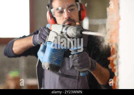 Construction worker working wrecking wall using rotary hammer in a house under renovation Stock Photo