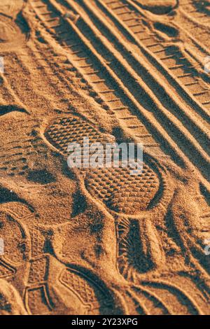 Footstep imprint and tire track tread marks in dust and sand, selective focus Stock Photo