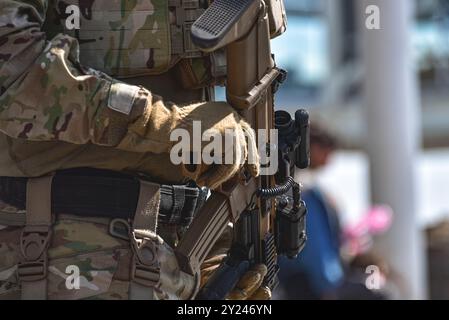 Soldier is holding a modern assault rifle with a scope and tactical gear, representing military preparedness and security Stock Photo