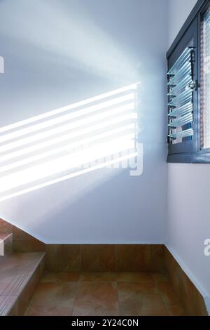 Empty white room with tiled floor and sunlight cast shadow on the wall. Interior inside house building. Stock Photo