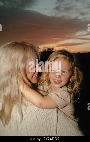Mom and child watch sunset in field Stock Photo