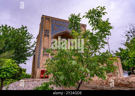 A building with a red door sits in front of a tree Stock Photo