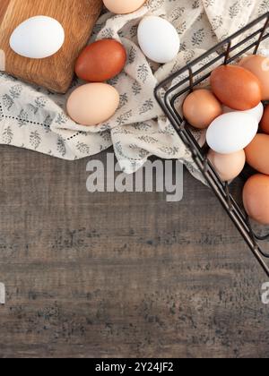 Eggs in a wire basket on a textured cloth and wooden background Stock Photo