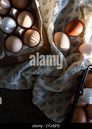 Eggs in a carton and basket on a patterned cloth with soft lighting Stock Photo