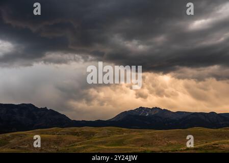 Dark, heavy clouds hover over a range of hills and distant mountains. Stock Photo