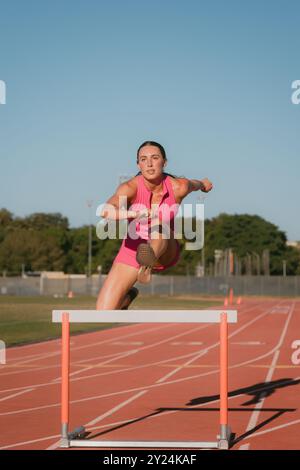 Female track athlete hurdling on track Stock Photo