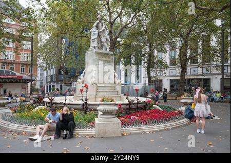 Daytime scene with people around the Shakespeare fountain and statue in Leicester Square gardens London England UK Stock Photo