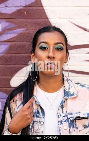 Indian woman in stylish denim outfit poses in an urban, architectural setting with geometric lines and cityscape views Stock Photo
