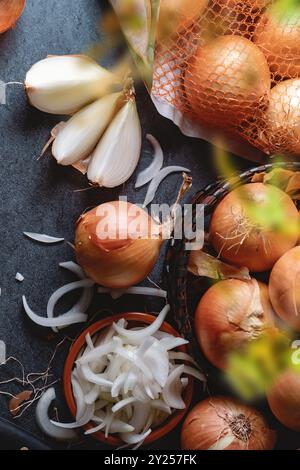 A lot of onions in a basket and plates on a dark and elegant dark textural background. Stock Photo