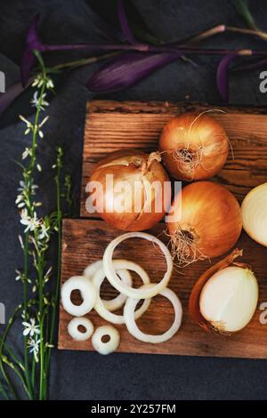 A lot of onions in a basket and plates on a dark and elegant dark textural background. Stock Photo