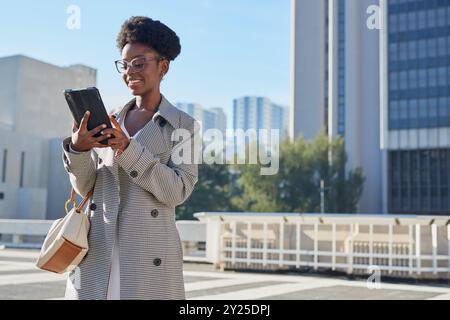 Smiling Woman Using Tablet in Urban Business Environment Stock Photo