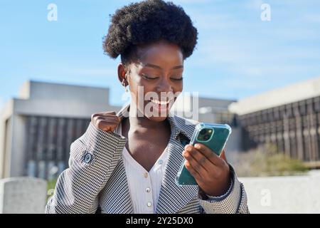 Joyful Woman Celebrating Success on Mobile Phone Outdoors Stock Photo