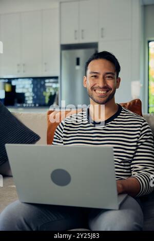 A man smiles while using a laptop computer on the couch Stock Photo