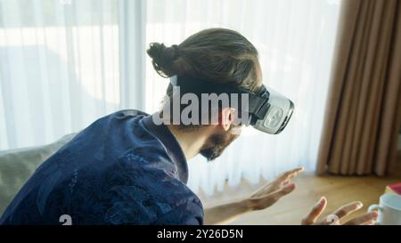 man wearing a VR headset explores virtual reality experience. Interacting with the virtual environment, the advanced technology's engagement. Stock Photo