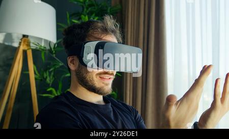 man immersed in a virtual reality experience wears a VR headset, interact with the digital environment. Stock Photo