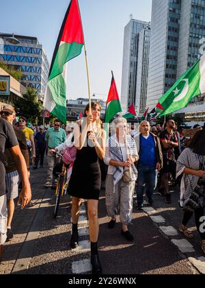 Stockholm, Sweden - September 7 2024: A public protest for Palestine and against Zionism in central Stockholm. A young woman, smiling and holding a Pa Stock Photo