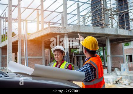 Team engineers holding blueprint project working outdoors building side with blueprints on a worksite, engineering and architecture concept, Engineers Stock Photo