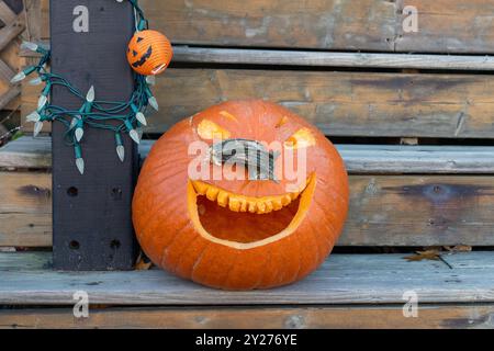 Fall decorations for Halloween holiday. Carved pumpkin on outdoor wooden stairs. Copy space Stock Photo