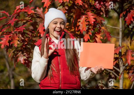 teen girl make an offer. winking girl offering advertisement in autumn nature. fall seasonal discount. offering autumn tips. school time in fall. best Stock Photo