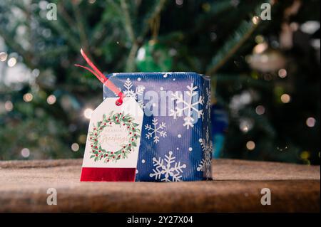 Square giftbox wrapped in snowflake paper with gift tag Stock Photo