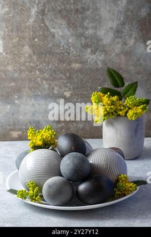 modern still life composition featuring various textured ceramic spheres and black easter eggs, complemented by vibrant yellow flowers Stock Photo