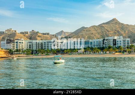 Qantab village white resort houses on the shore view from the sea bay with mountains in the background, Muscat, sultanate Oman Stock Photo