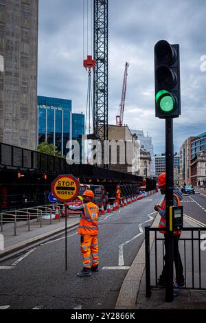 Building Work traffic control in the City of London UK. Manual traffic control by building workers for overhead crane work. Stock Photo