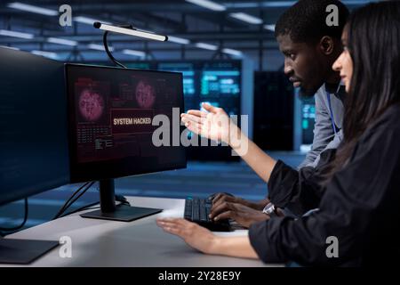 Programmers doing teamwork in server hub trying to protect hardware from hacker stealing information. Colleagues in data center workspace trying to fix security breach alert caused by virus Stock Photo