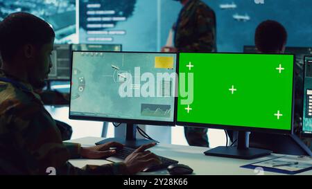 Private monitors national guard activity with military CCTV satellite system, working with a greenscreen display on pc in command center. IT reconnaissance operator tracking ships. Camera A. Stock Photo