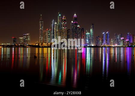 The Dubai modern architecture skyscrapers skyline at night reflected on the waters of the Persian gulf, United Arab Emirates Stock Photo