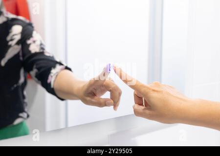 Closeup of a Hand Interacting with a Digital Mirror: Touchscreen Interface with LED Light, Modern Gesture Control, and Technology in a Bathroom Settin Stock Photo