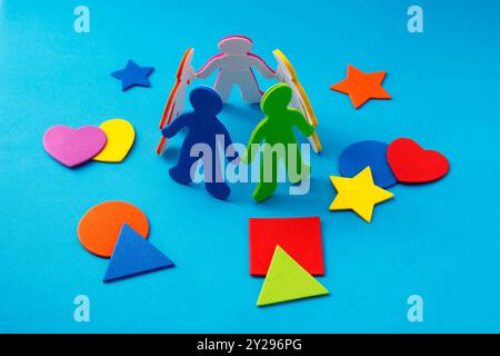 Silhouettes of people forming a circle and surrounded by colorful geometric figures made of rubber foam Stock Photo