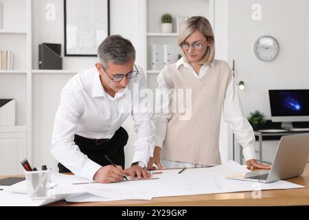 Architects making engineering drawing at wooden table in office Stock Photo
