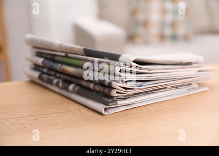 Stack of newspapers in different languages on table indoors Stock Photo