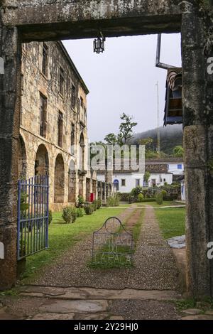 View through a stoney entrance gate to historic restored museum of Sanctuary Caraca with arches and windows, Minas Gerais, Brazil, South America Stock Photo