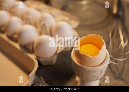 large broken chicken egg in a special container on the background of a box with eggs, concept of fresh organic eggs Stock Photo