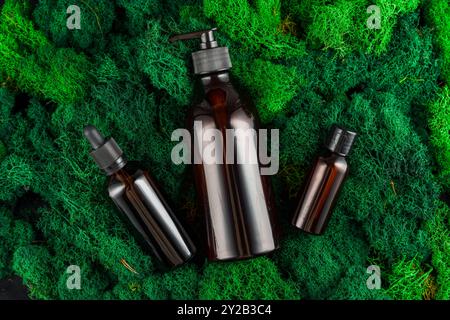 Brown glass dropper bottles arranged on green moss in a natural setting Stock Photo