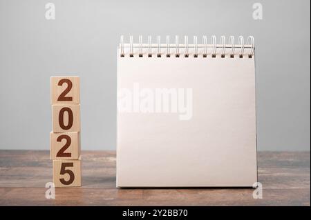 2025 mockup notepad. 2025 cubes wooden table background. New Year. plans for 2025, space for your text on notepad, mockup calendar Stock Photo