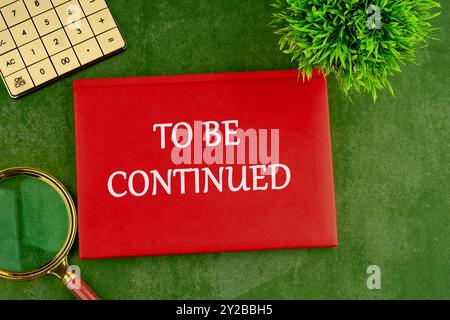 TO BE CONTINUED text written on the red book, business on a green saturated background Stock Photo