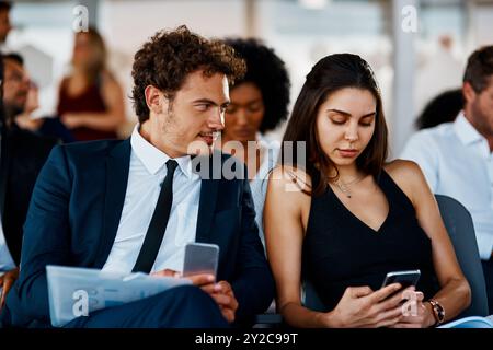 Business people, smartphone and flirt in conference room, social media and networking. Employees, coworkers and participants in seminar, cellphone or Stock Photo