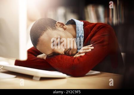 Man, university student and tired with sleep in library by computer with burnout, exhausted or rest for learning. African person, fatigue and dream by Stock Photo